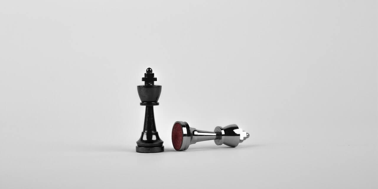 black-chess-piece-stood-next-to-beaten-white-chess-piece