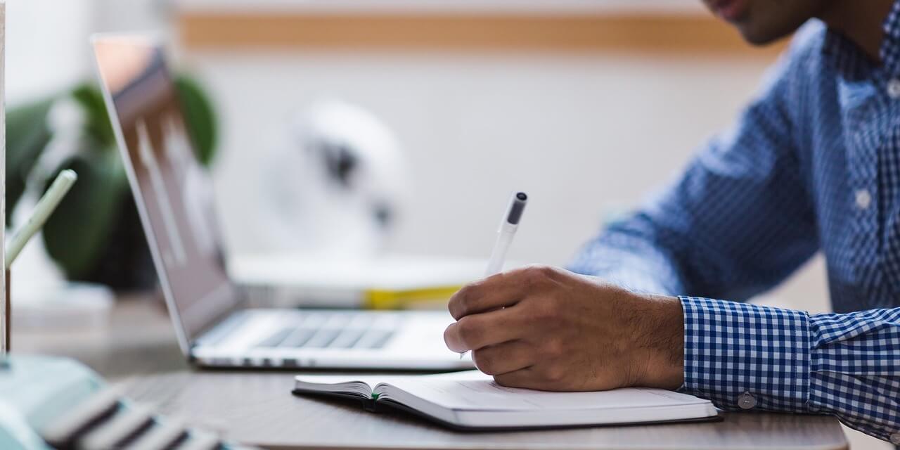 man-making-notes-while-at-computer
